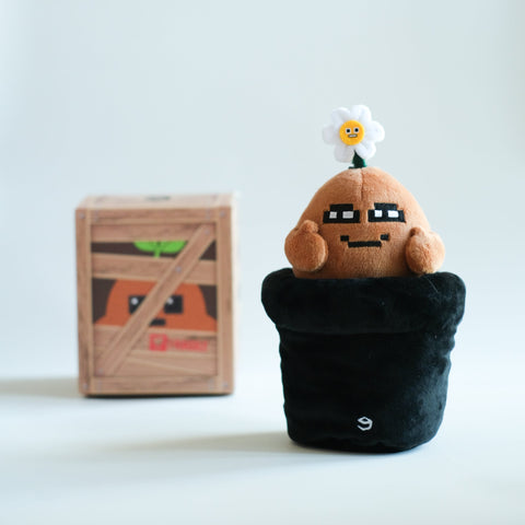 potatoz plush toy resembling a character from a video game, with a wooden crate in the background.