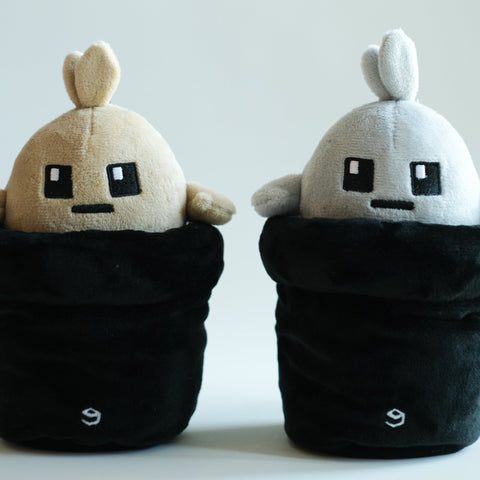 Two Potatoz plush toys resembling characters from a video game, one beige and one white, on a light gray background.