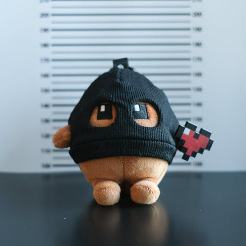 Potatoz plush toy with a black hood and red heart on a dark surface with a light gray background